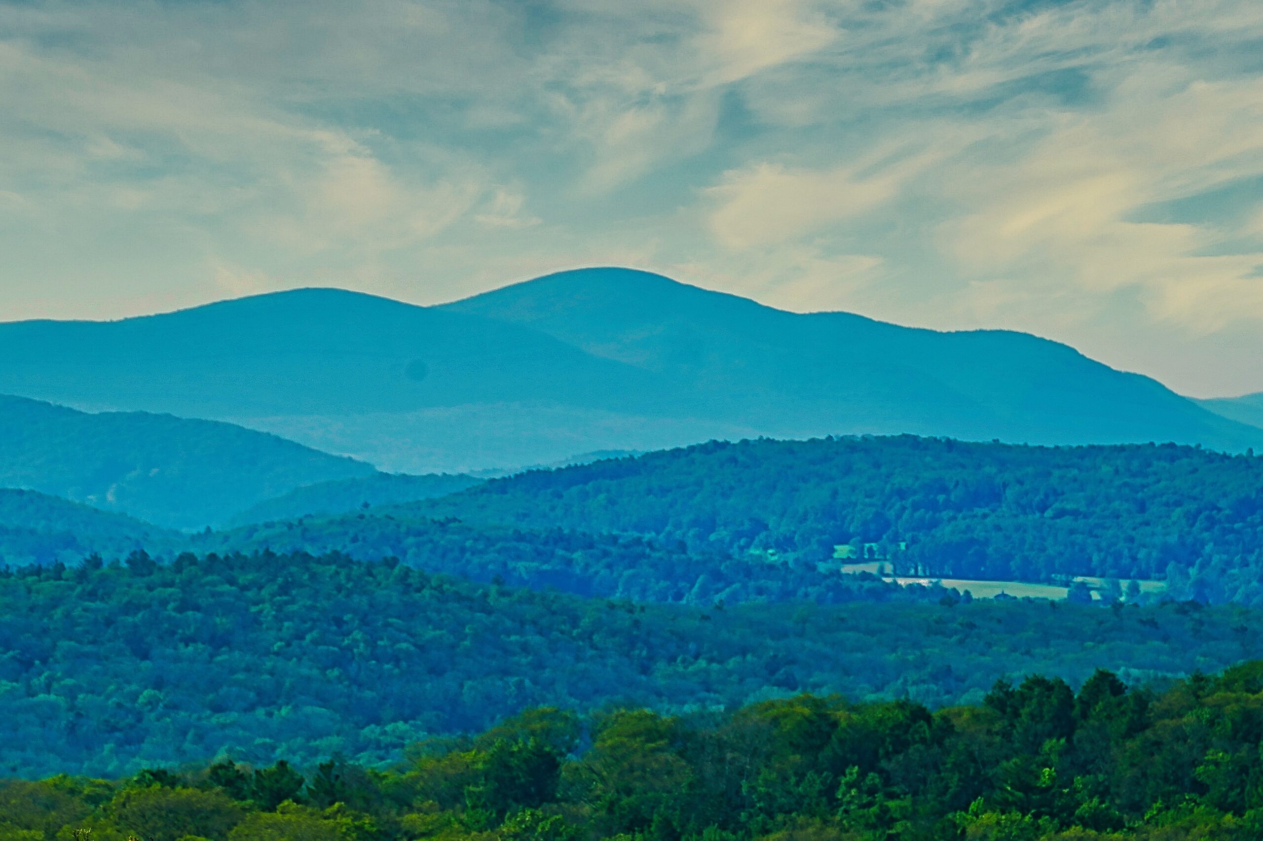 Layers of blue mountains above a green wooded valley.