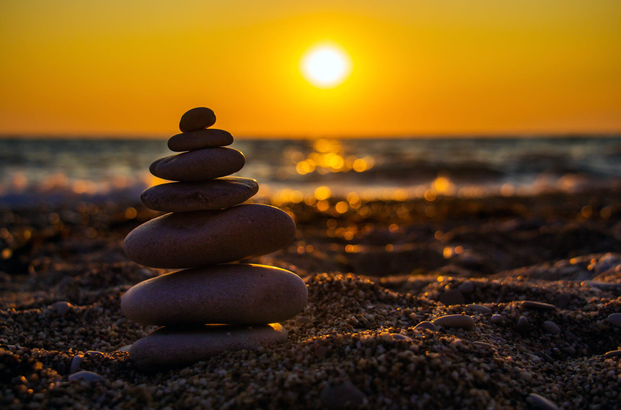 Smooth stones stacked on a beach in warm sunset light.